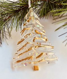 a glass christmas tree ornament hanging from a pine branch