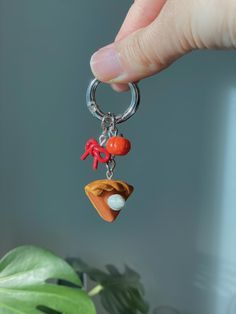 a hand holding a keychain with charms on it and a potted plant in the background