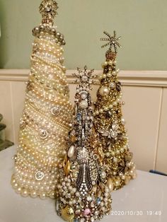 three small christmas trees made out of pearls and other beads are sitting on a table