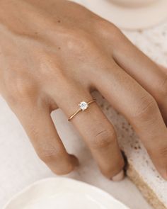 a woman's hand with a diamond ring on her finger, next to a piece of bread