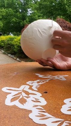 a person is painting on the ground with white paint and an object in their hand