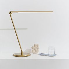 a desk lamp sitting on top of a white table next to a glass of water