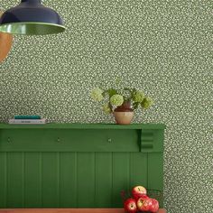 a green bench in front of a wallpapered room