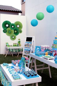 an outdoor birthday party with blue and green decorations, paper lanterns and desserts on tables