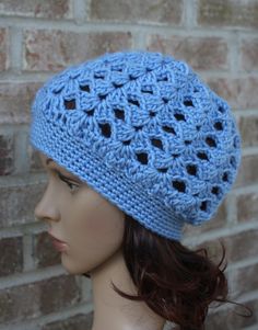 a mannequin head wearing a blue crocheted hat on top of a brick wall