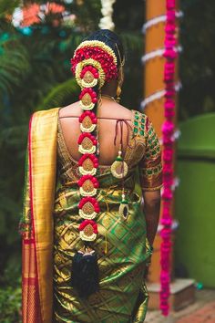 a woman wearing a green sari with red and gold accessories