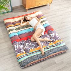 a woman laying on top of a multicolored bed