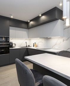 a modern kitchen with marble counter tops and black cabinets, along with gray chairs around the table