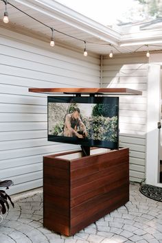 a flat screen tv sitting on top of a wooden stand in front of a house