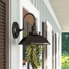 an outdoor light hanging on the side of a house with flowers in vases next to it