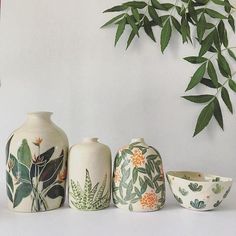 three vases and a bowl are sitting on a table