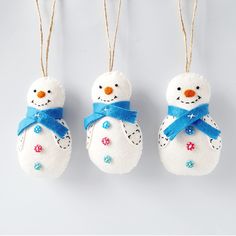 three snowman ornaments hanging from twine with blue ribbon and bows on white background