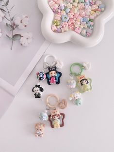 various keychains and charms on a table next to a vase with flowers in it