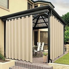 a patio covered in curtains next to a house