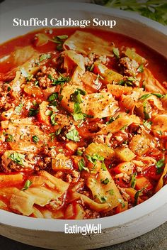 a white bowl filled with pasta and meat covered in tomato sauce, garnished with parsley