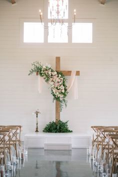 a cross decorated with flowers and greenery sits in the middle of an empty church