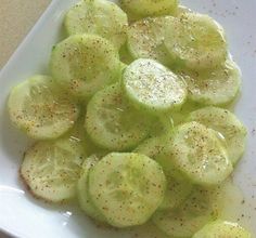 sliced cucumbers on a white plate with seasoning