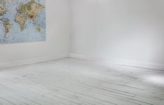 an empty room with a world map hanging on the wall and wooden floors in front of it