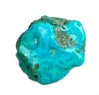 a piece of turquoise colored rock sitting on top of a white surface