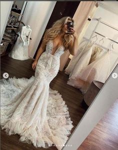 a woman taking a selfie in front of a mirror wearing a white wedding dress