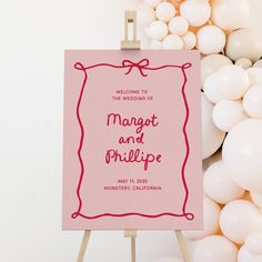 a welcome sign with balloons in the background and a pink card on an easel