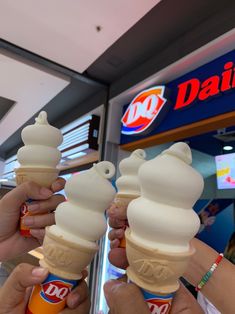 three people holding ice cream cones in front of a dairy store