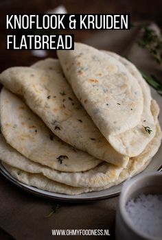 four pita breads on a plate with salt and pepper