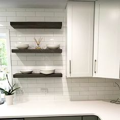 a kitchen with white cabinets and black counter tops, along with shelves above the sink