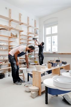 two men working on pottery in a studio