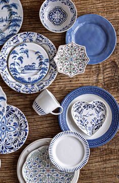 a table topped with lots of blue and white dinnerware on top of a wooden table