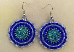 This item is a pair of hand beaded earrings. The center is a imitation druzy rhinestone. The beads are size 11/0 seed beads in Royal Blue and Silver with clear and silver beads for the edges. Blue Round Beaded Earrings With Colorful Beads, Blue Round Beaded Earrings, Blue Round Crystal Earrings, Blue Round Beaded Earrings With Spacer Beads, Crystal Beaded Earrings With Round Beads, Blue Bead Cap Drop Earrings, Blue Beaded Drop Earrings With Bead Caps, Blue Dangle Jewelry With Bead Caps, Blue Beaded Crystal Earrings With Round Beads