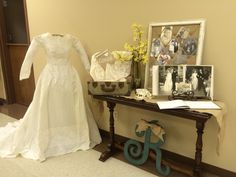 a wedding dress is sitting on a table next to a vase with flowers in it