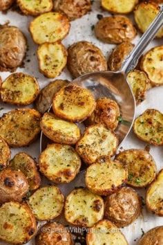 cooked potatoes on a baking sheet with a spoon in the middle and seasoning next to them