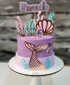 a purple and blue cake with mermaid decorations