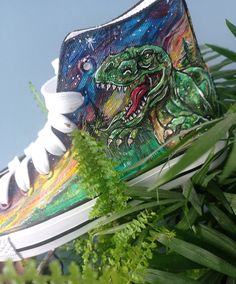 a pair of sneakers painted with an image of a dinosaur