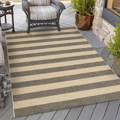 an outdoor area rug with chairs and potted plants