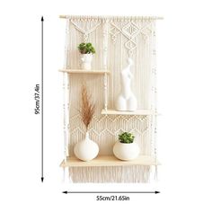 three white vases are sitting on the shelves with plants in them and one is holding a plant