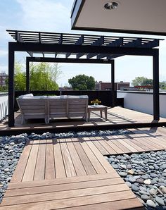 a wooden deck with two benches under a gazebo