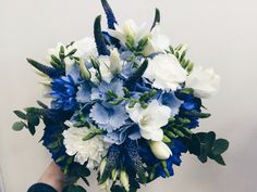 a bouquet of blue and white flowers in someone's hand