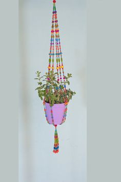 a potted plant hanging from the ceiling with beads and tassels on it