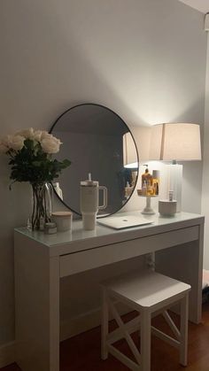 a white desk with a mirror and vase on it