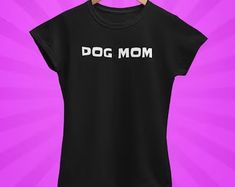 a black dog mom t - shirt hanging on a clothesline against a purple background