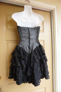 "Vintage size small black dress with leather sweetheart bodice and ruffle lace layered skirt. Zips up the back. In good vintage condition but the puller on the zipper need to be reconnected somehow - see last photo. Measurements taken across front laid flat 16\" across front armpit to armpit 12.5\" across front of waist -doubles to 25\" 19\" across front of hips 26\" length armpit to bottom" Black Fitted Corset Dress With Ruffles, Steampunk Corset Dress With Ruffles For Alternative Fashion, Black Gothic Strapless Corset Dress, Black Underbust Corset Dress With Attached Cancan, Vintage Fitted Corset Dress For Alternative Fashion, Black Vintage Underbust Corset Dress, Steampunk Lace Fitted Corset Dress, Black Steampunk Corset Dress For Party, Black Lined Corset Dress With Fitted Bodice