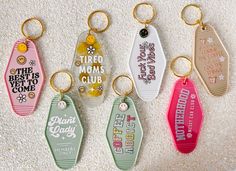 four different colored key chains are hanging on the floor with their names and phrases printed on them