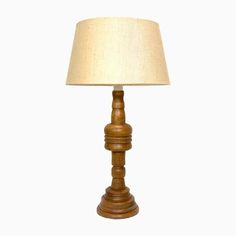 a wooden table lamp with a white shade on it's base, against a white background