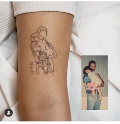 a man holding a baby in his arms with a tattoo on it's arm