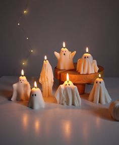 some white candles with ghost faces and lights in the shape of ghosts on top of them