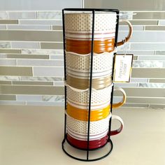 a stack of coffee mugs sitting on top of a counter next to a tile wall