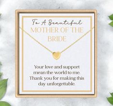 a mother of the bride necklace with a heart charm on it, sitting in front of some leaves