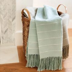 a basket with two towels and a blanket on it next to a fireplace in a living room